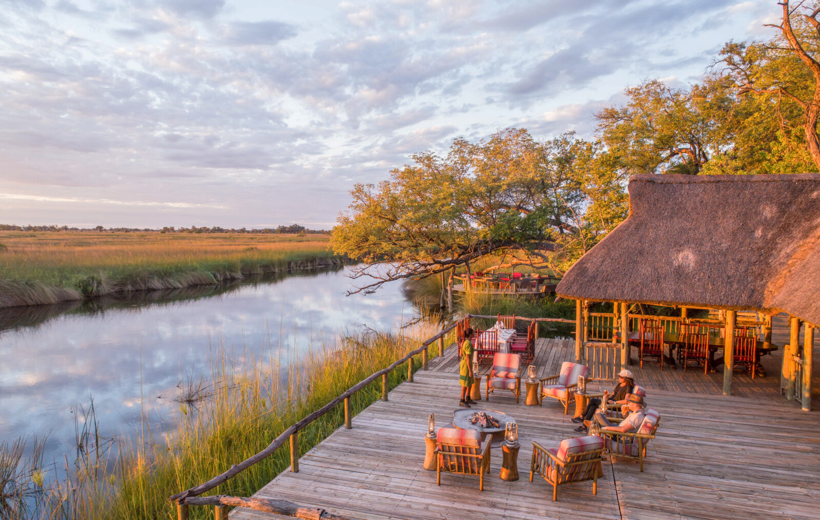 The thatched main area and deck of Camp Xakanaxa at the water edge, Moremi Game Reserve, Botswana