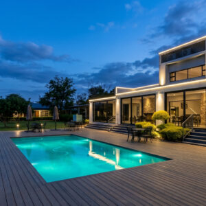 The lit swimming pool, timber deck and glazed public rooms at Travelodge Kasane at dusk, Botswana
