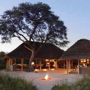 The thatched main area and fire of Camp Kalahari under acacias on Brown Hyena Island, Makgadikgadi, Botswana