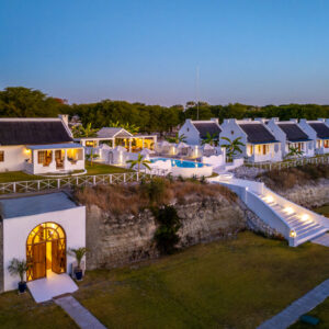 Aerial view of the whitewashed cottages, terraces and swimming pool at Grays Eden on the Thamalakane River near Maun, Botswana