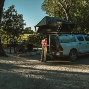 A vehicle with a rooftop tent pitched under mature riverine trees at the SKL Khwai campsites near Moremi North Gate, Botswana