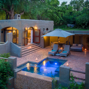 A suite with a lit private plunge pool and terrace among riverine trees at Chobe Game Lodge, Chobe National Park, Botswana