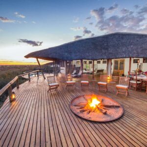 The fire deck and thatched main area of Tau Pan Camp above the pan at dusk, Central Kalahari Game Reserve, Botswana