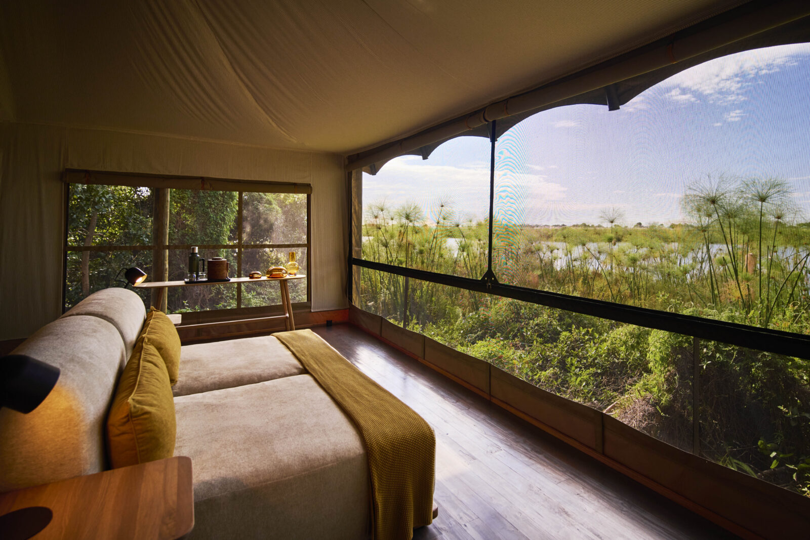 A tent lounge with mesh windows looking over papyrus and the lagoon at Xugana Island Lodge, Okavango Delta, Botswana