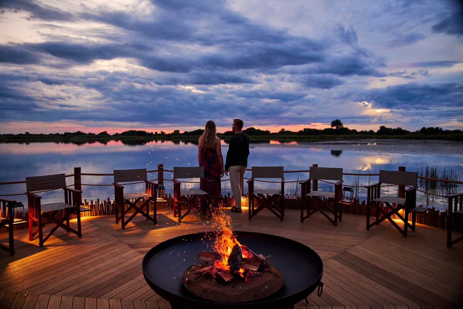 The overwater fire deck at Xugana Island Lodge at dusk, looking across Xugana Lagoon in the Okavango Delta, Botswana
