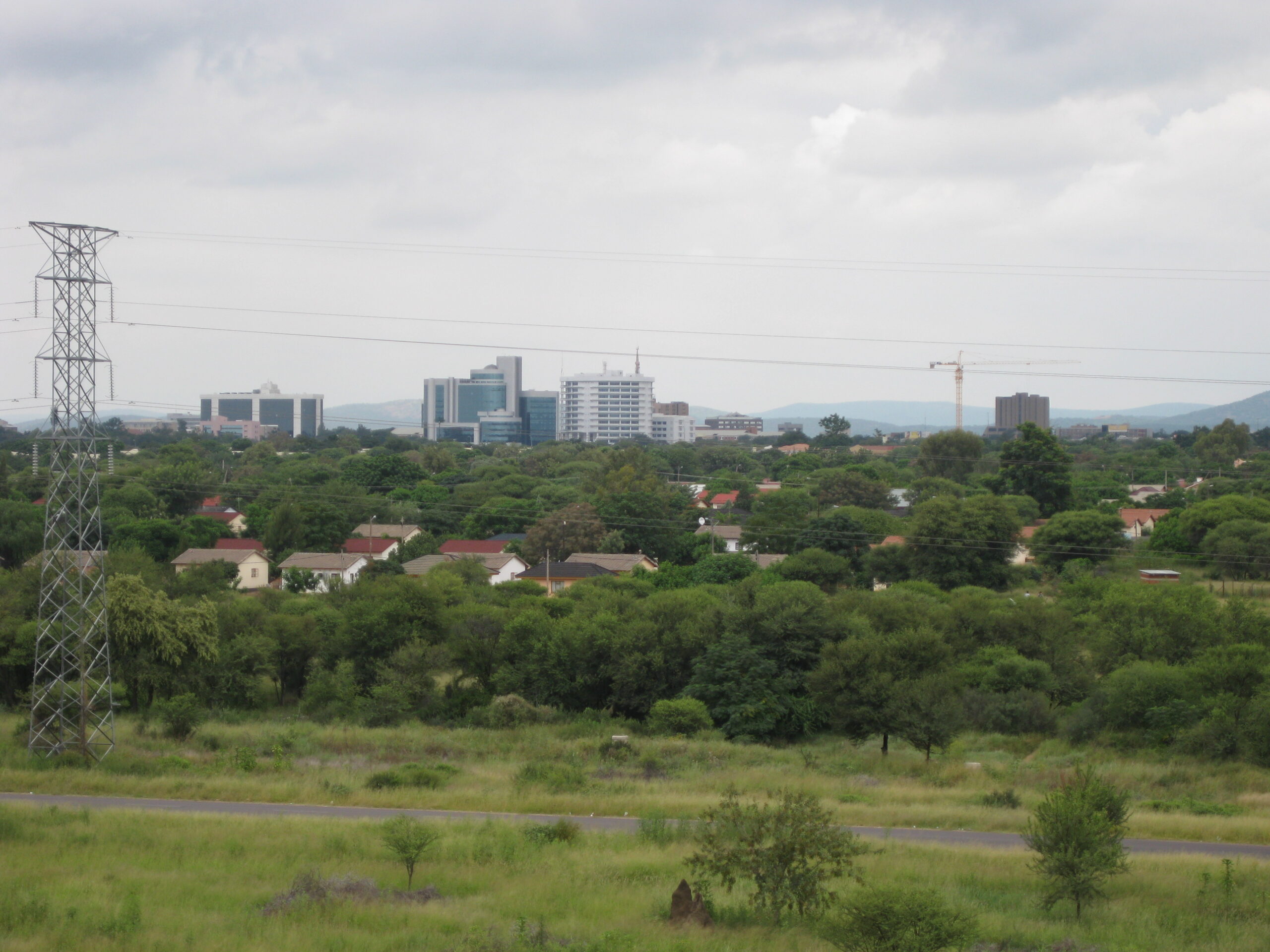 The skyline of Gaborone, Botswana, seen across low green bush (destination context, not a photograph of this tour)