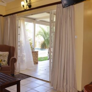 The living area of a self-catering cottage opening onto the garden at Chobe River Cottages, Kasane, Botswana