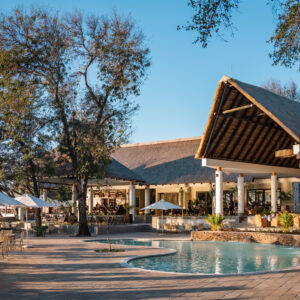 The swimming pool, parasols and thatched main building at Chobe Safari Lodge in Kasane, Botswana