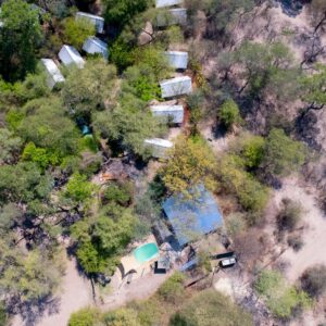 Aerial view of the tents, thatched buildings and swimming pool of Delta Rain Sitatunga Camp set in mopane bush outside Maun, Botswana