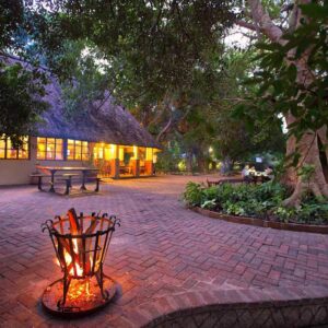 Fire pit and lit thatched building on the promenade at Island Safari Lodge, Maun