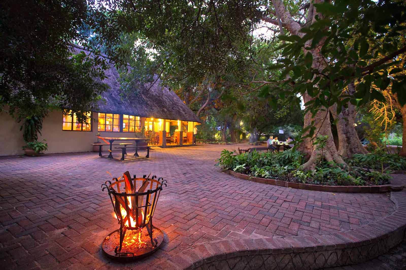 Fire pit and lit thatched building on the promenade at Island Safari Lodge, Maun