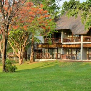 The thatched main building and river-facing rooms of Cresta Mowana Safari Resort and Spa seen across the lawns at Kasane, Botswana