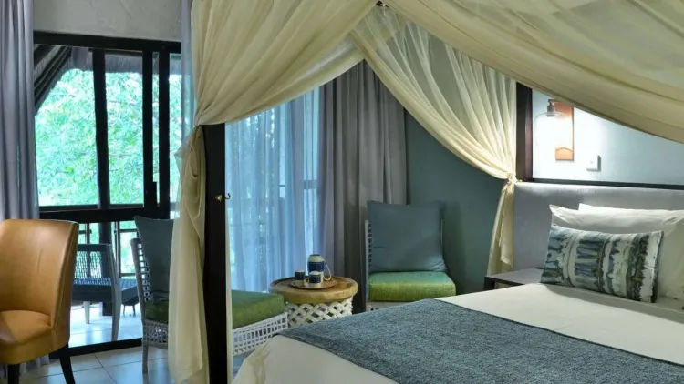 A guest room with a mosquito-netted bed and doors opening towards the Chobe River at Cresta Mowana Safari Resort and Spa, Kasane, Botswana