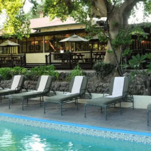 The swimming pool, loungers and shaded garden terraces at Cresta Riley's hotel in Maun, Botswana