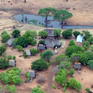 Aerial view of the thatched chalets, campsites and floodlit waterhole at Senyati Safari Camp near Kasane, Botswana