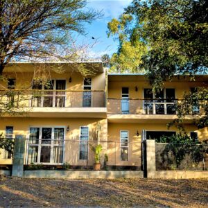 Two-storey guesthouse building among trees at Maun Waterfront Guesthouse