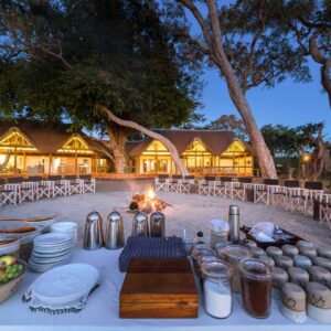The lit open-plan main building and fire circle at Splash Camp in the Kwara Concession, Okavango Delta, Botswana