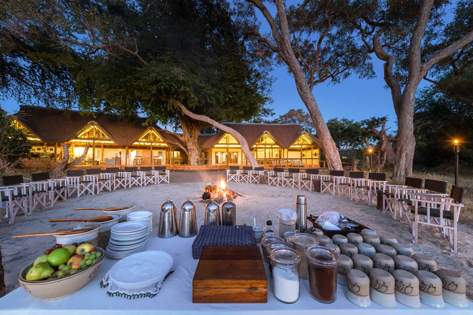 The lit open-plan main building and fire circle at Splash Camp in the Kwara Concession, Okavango Delta, Botswana