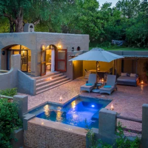 A suite with a lit private plunge pool and terrace among riverine trees at Chobe Game Lodge, Chobe National Park, Botswana